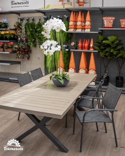 Ensemble table rectangulaire effet bois pieds X métal et chaises gris foncé, exposé dans une jardinerie.